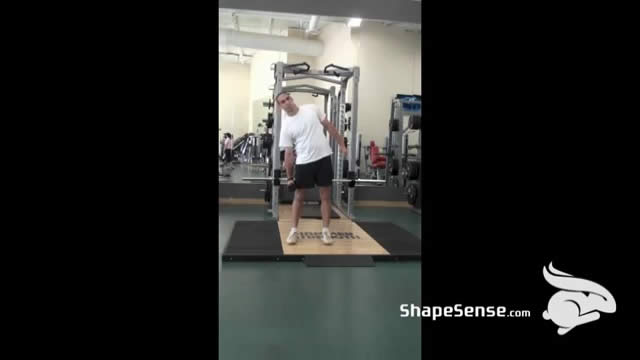 An image of a man performing the dumbbell side bend exercise.