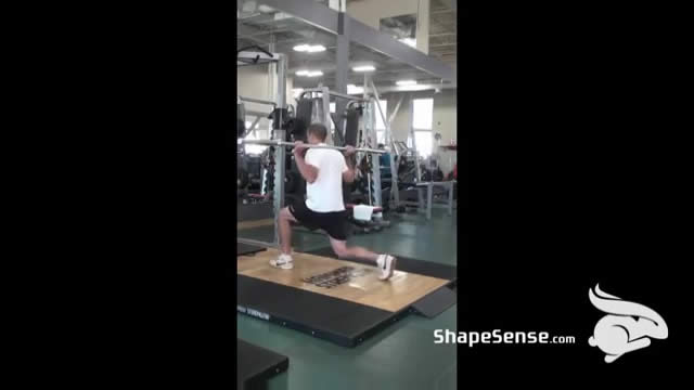 An image of a man performing the barbell lunge exercise.