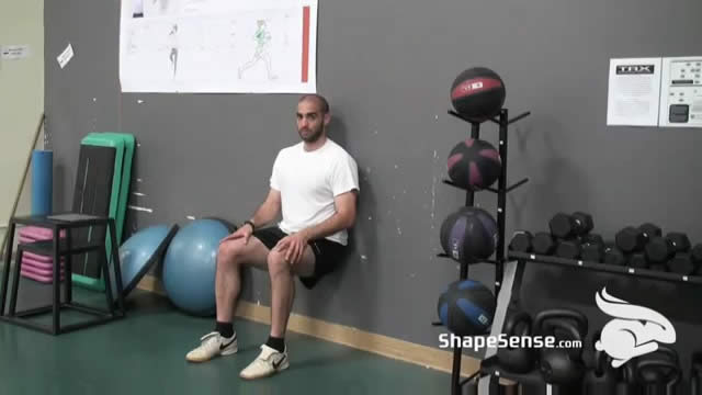 An image of a man performing the wall sit repetitions exercise.