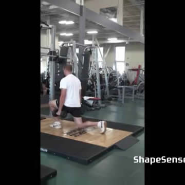 An image of a man performing the dumbbell lunge exercise.