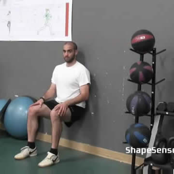 An image of a man performing the wall sit repetitions exercise.