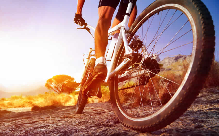 A man mountain biking on rough terrain.