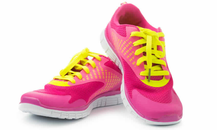 A pair of pink running shoes with yellow laces.