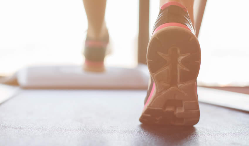 A pair of feet walking on a treadmill.