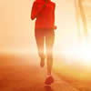 A woman running on a road with the sun behind her.